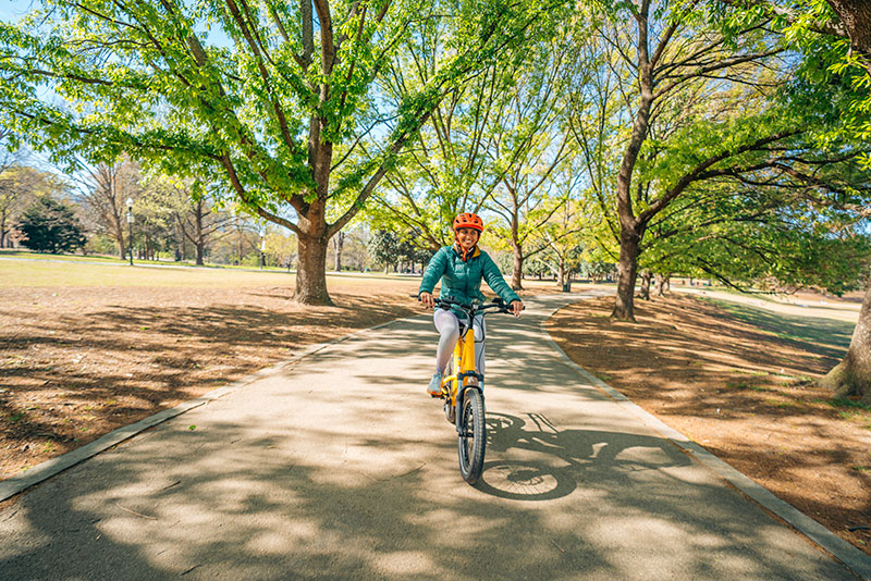 Hello Nature host Misha Euceph rising a bicycle through a park.