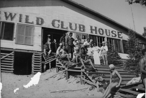 A group sitting on the steps of the Wild Club House