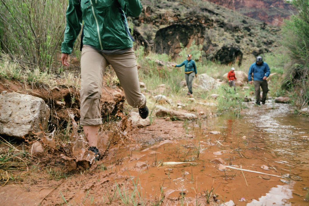A hiker splashes through a muddy creek in the Grand Canyon.