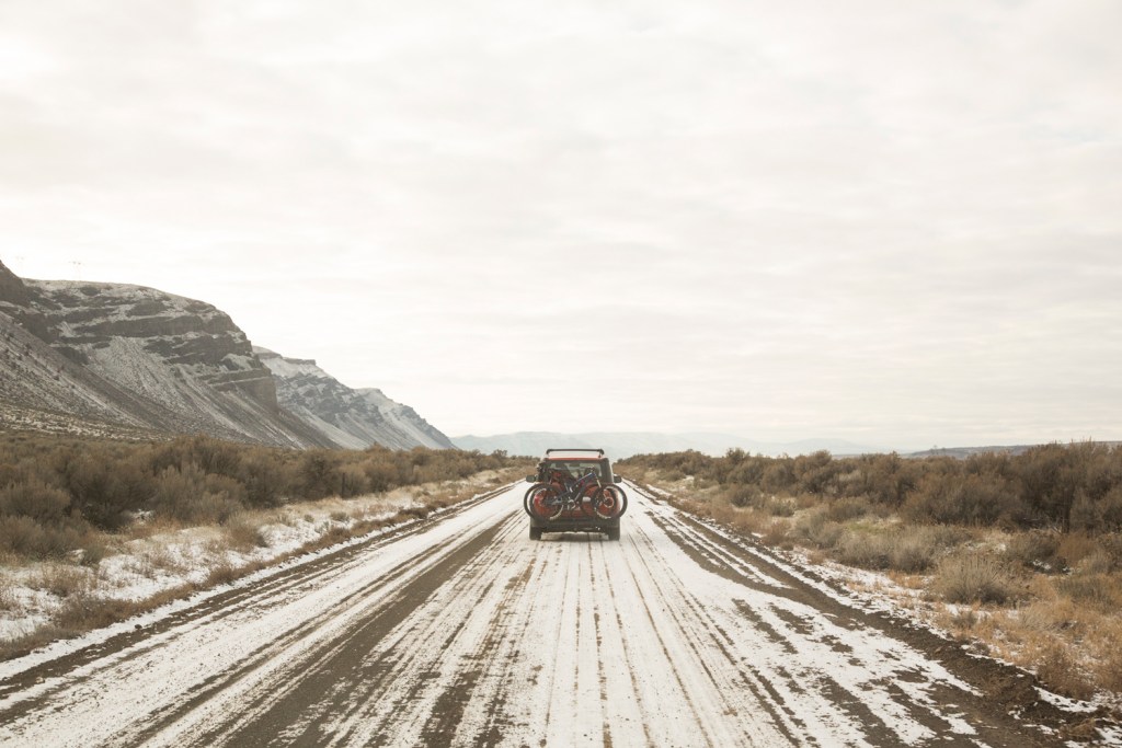 car driving through the wintry desert with snow-covered roads