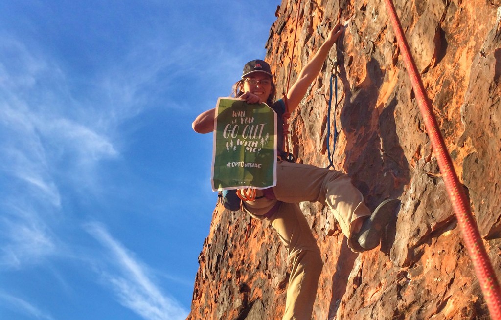 girl rock climbing with Opt Outside sign