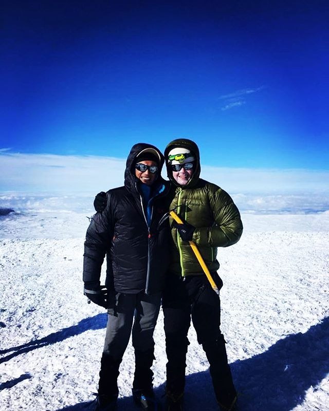 two people successfully summit a mountain