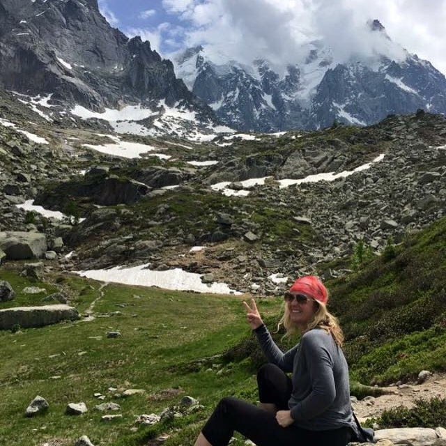 woman sitting near a trail with mountains in the background