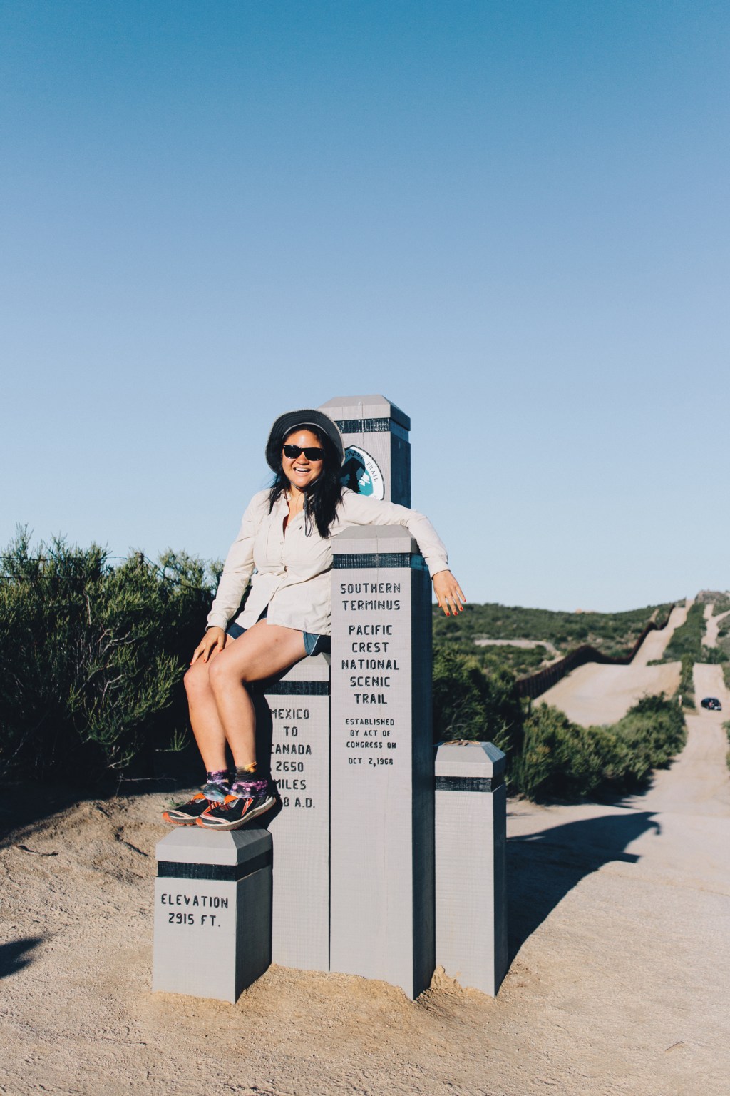 karen wang sits on PCT trail signs