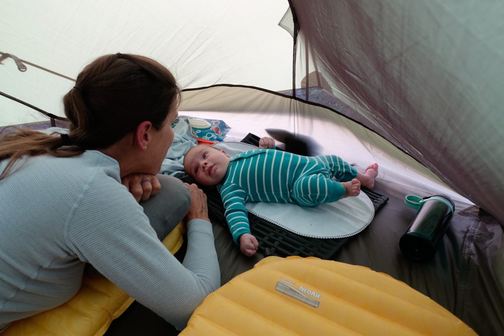 a baby and his mom hanging out in a tent during a backpacking trip