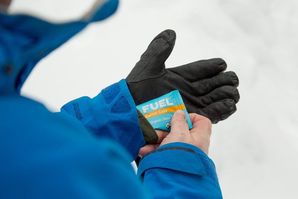 skier inserting energy bar into glove to keep warm