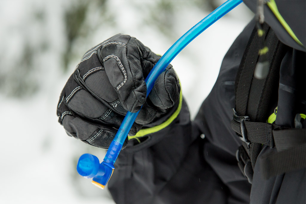 skier blows air out of CamelBak hose to keep it from freezing in the winter