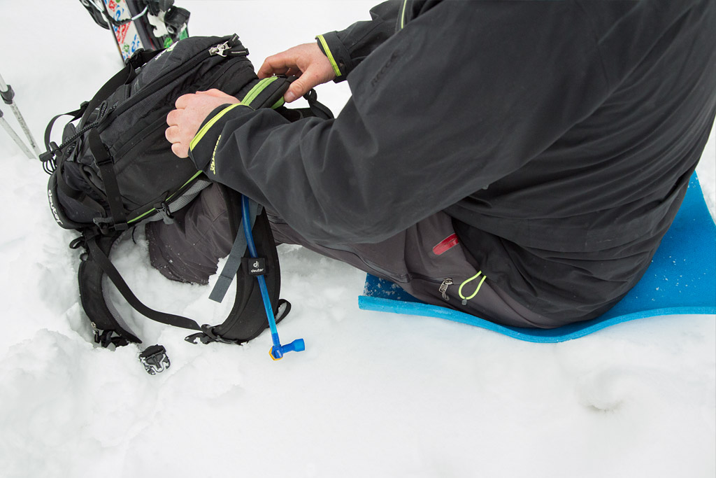 skier takes a break and sits on a lightweight mat to protect him from the cold snow