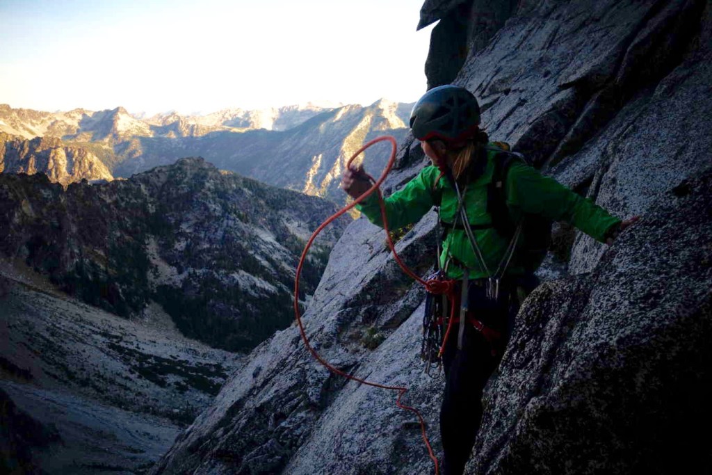 female flakes rope high on a rock wall