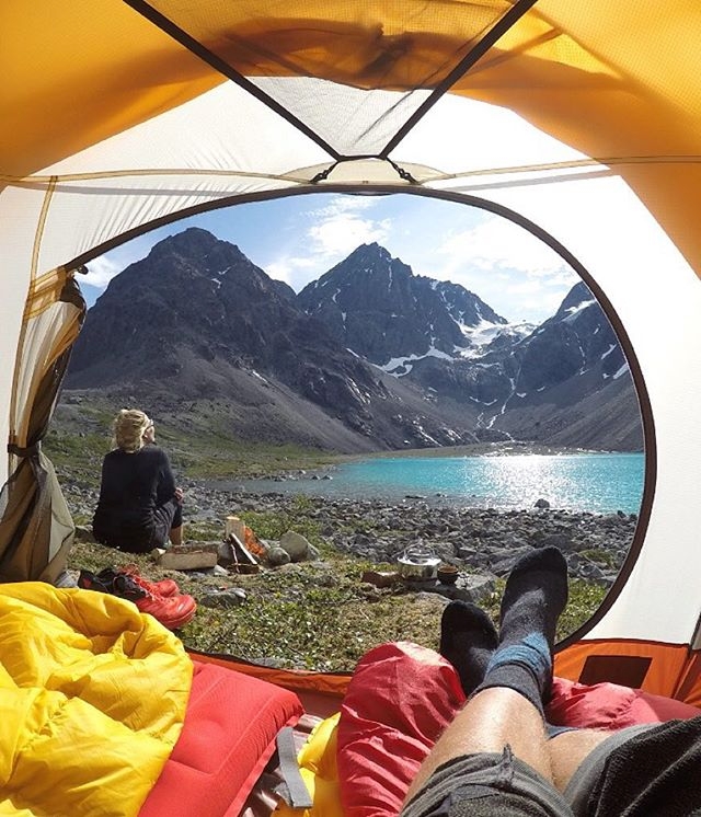 campers in tent look at glacier lake