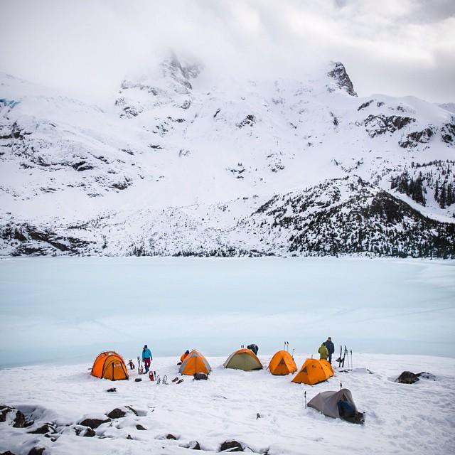 five tents next to a frozen lake on snow