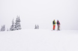 two skiers scoping out a line in whiteout conditions