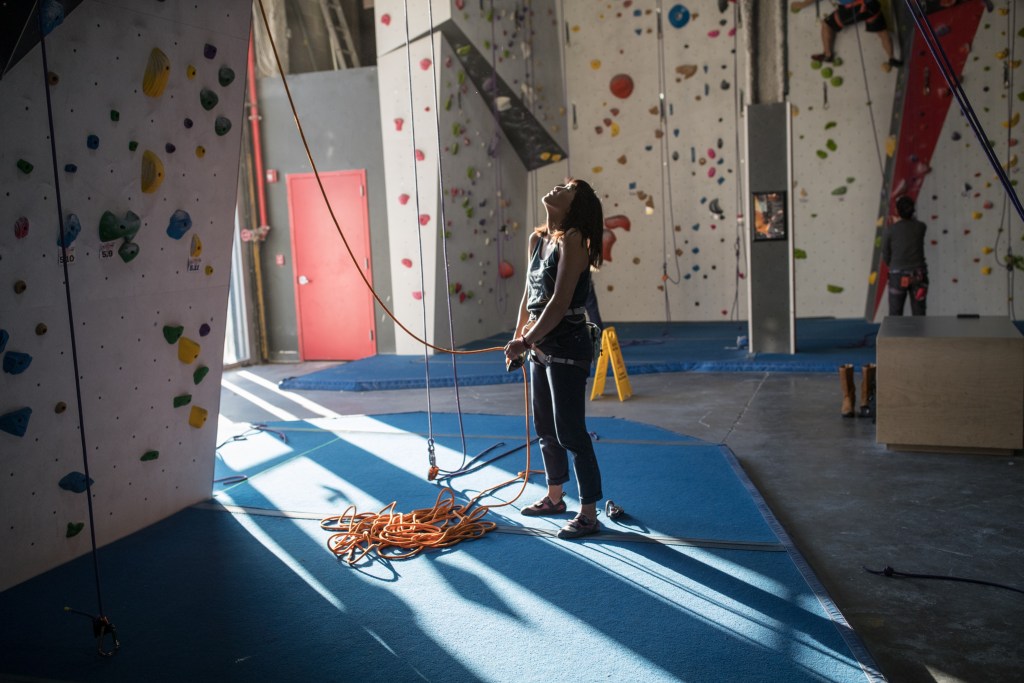 Shelma looking at a climbing route in a climbing gym.