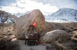 Shelma climbing a boulder with women supporting her.