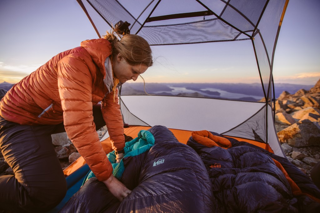 female making setting up tent and placing up her sleeping bag