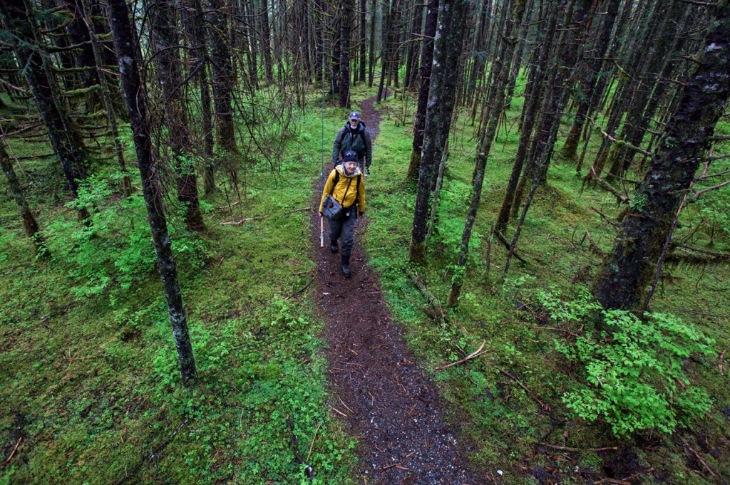 Terry Myers walks through a forest with fishing rods