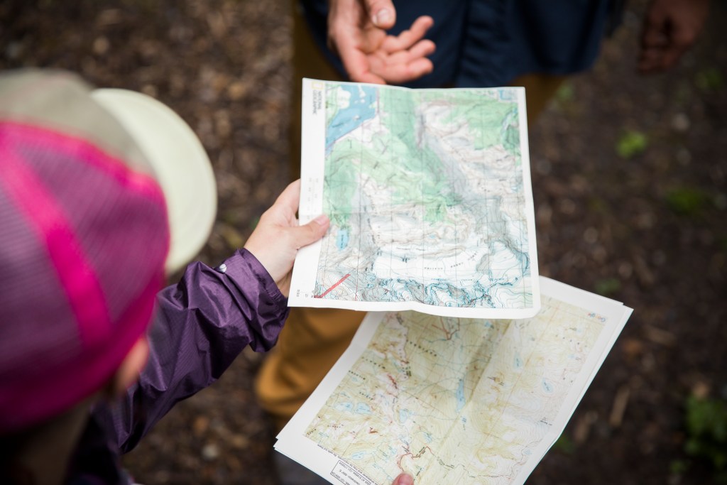 Backpacker holding two maps