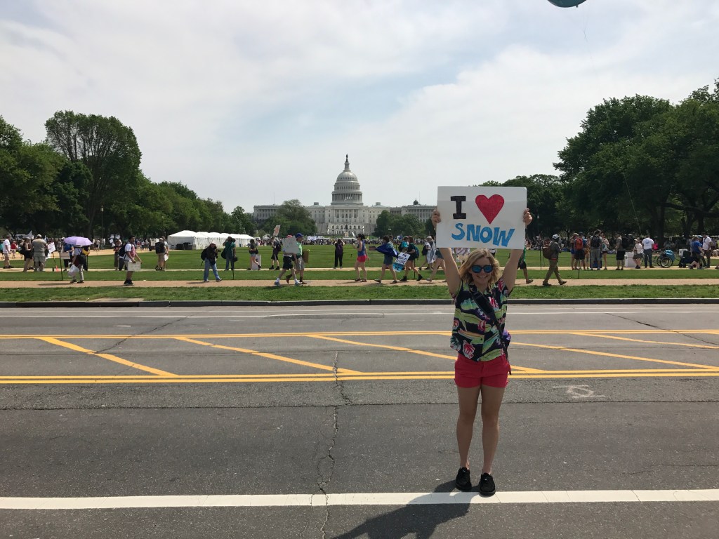 Caroline Gleich holding an I love snow sign in front of the White House