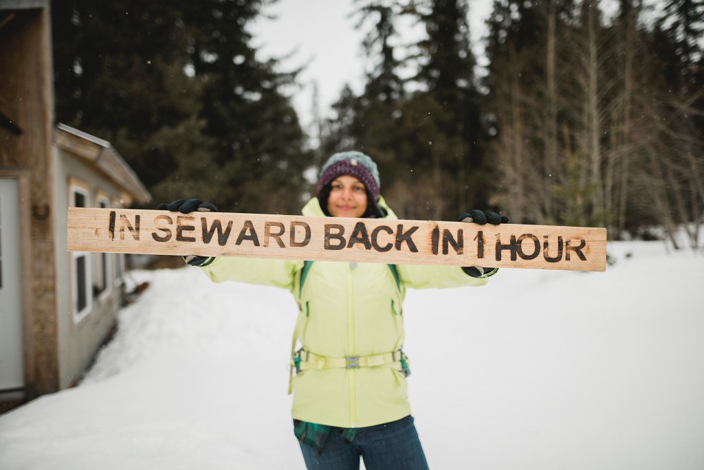 Whitney Anderson holding a "In Seward Back in 1 Hour" sign