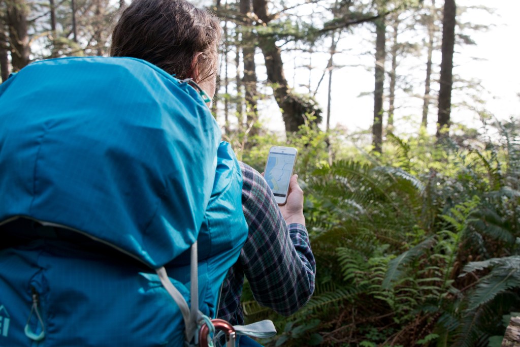 Person backpacking using their phone and the app.