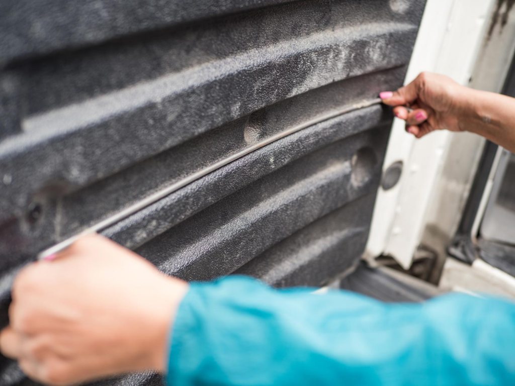 Person using wire as a guide to measure a van door