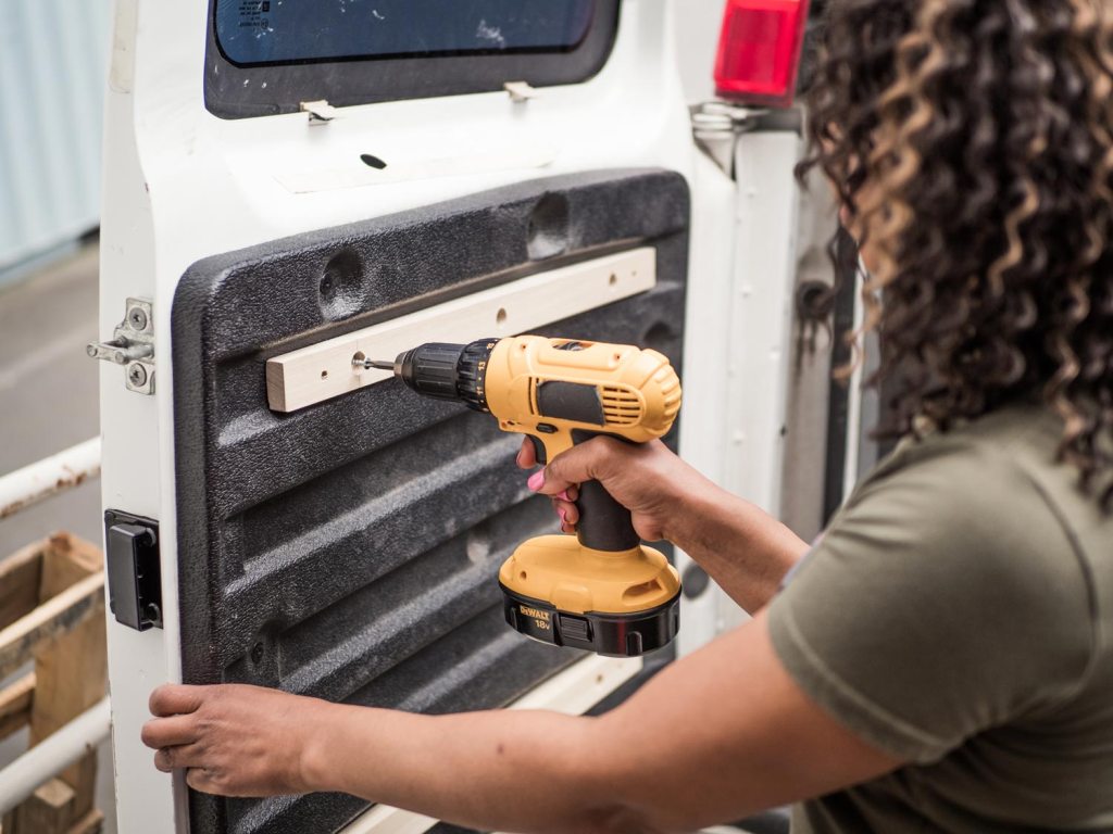 Woman drilling holes in a van door