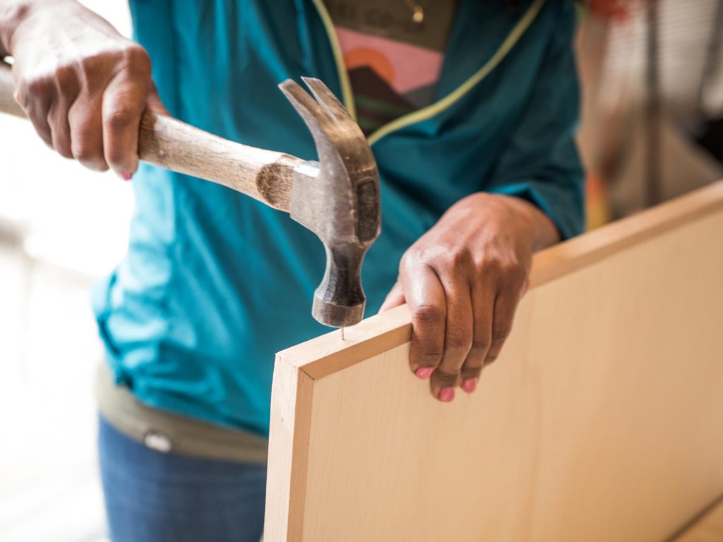 Person hammering sides of table trim in
