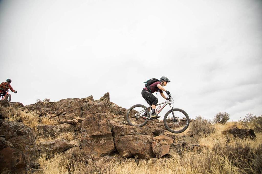 Mountain bike rider descending over rocks.