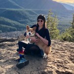 Corina sitting at the top of a hike with her corgi.