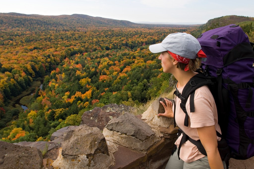 A backpacker looks out from the Escarpment Trail above Lake of the Clouds in Porcupine Mountains State Park in fall in Michigan's Upper Peninsula.