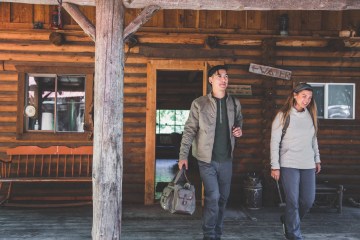 Two travelers leaving a log cabin