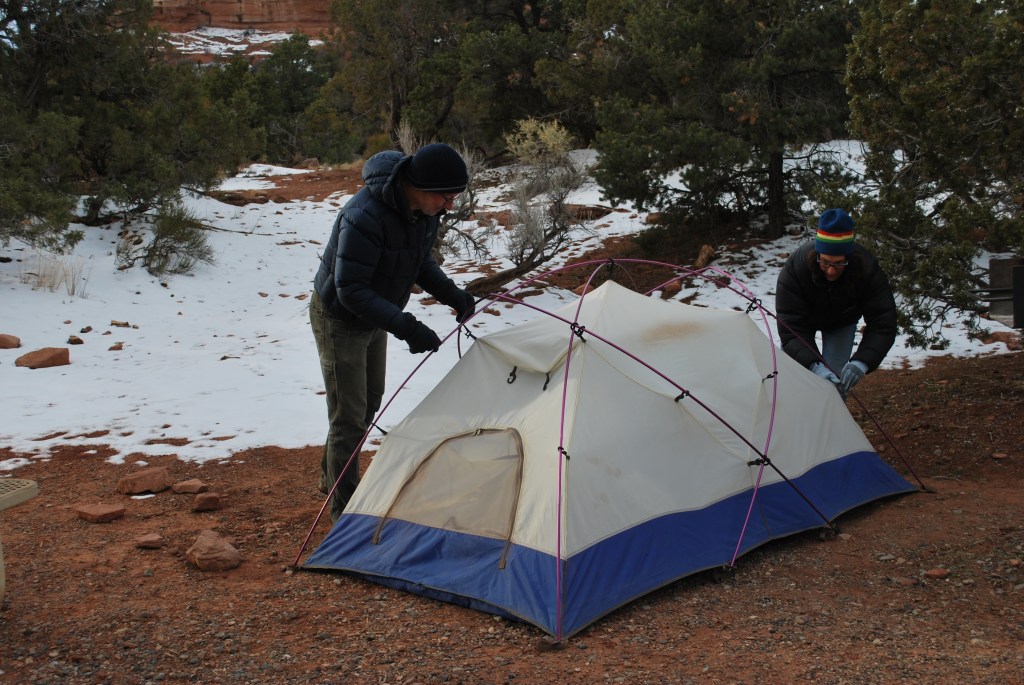 Two campers setting up a tent. 