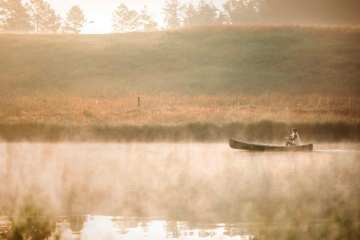 A woman paddling a canoe through a misty lake