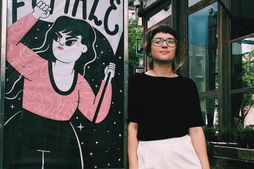 Camila Rosa is leaning against a photo booth featuring her art.