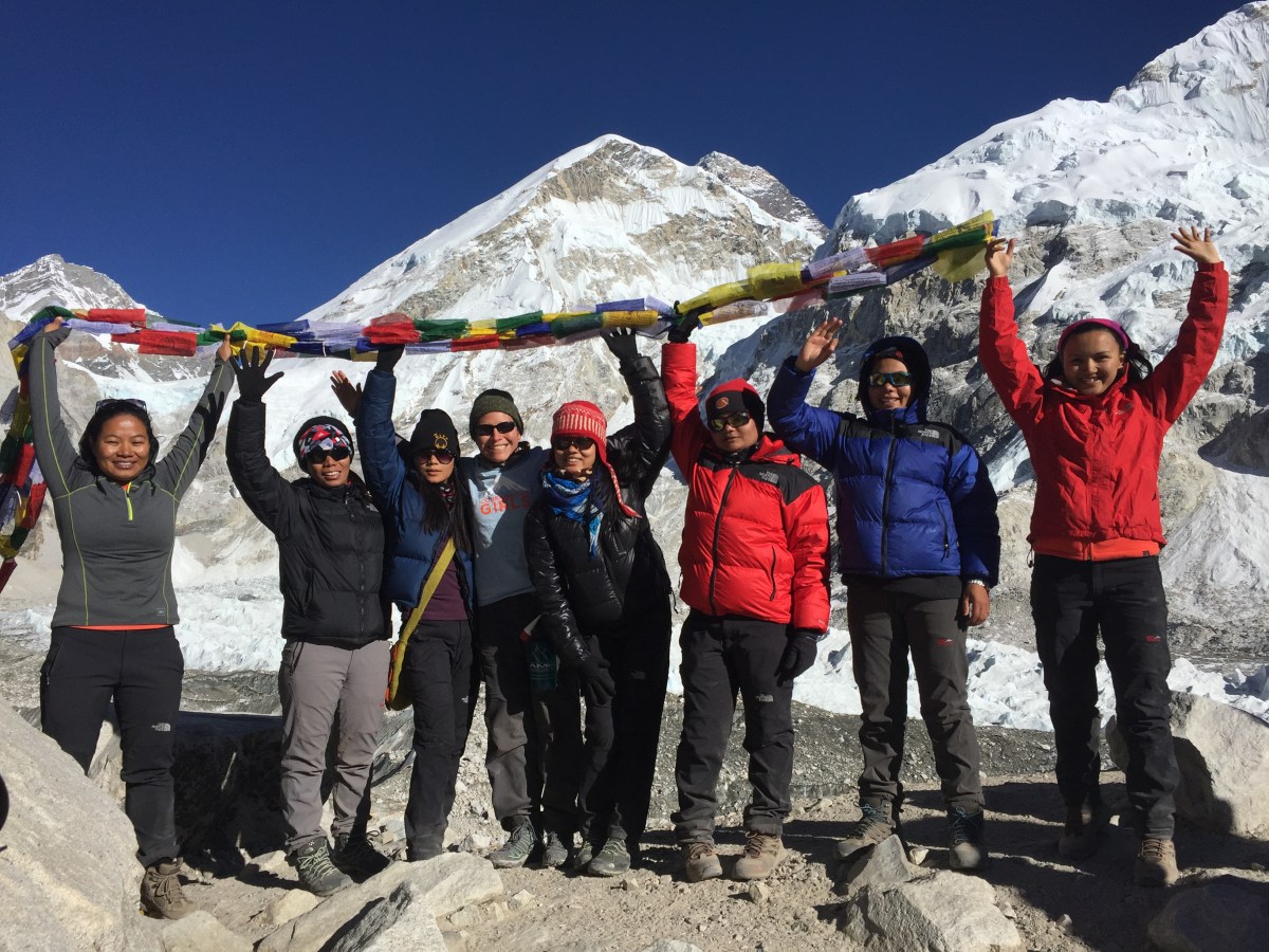Vasquez-Lavado and guides raise their hands to the sky holding prayer flags at Everest Basecamp.