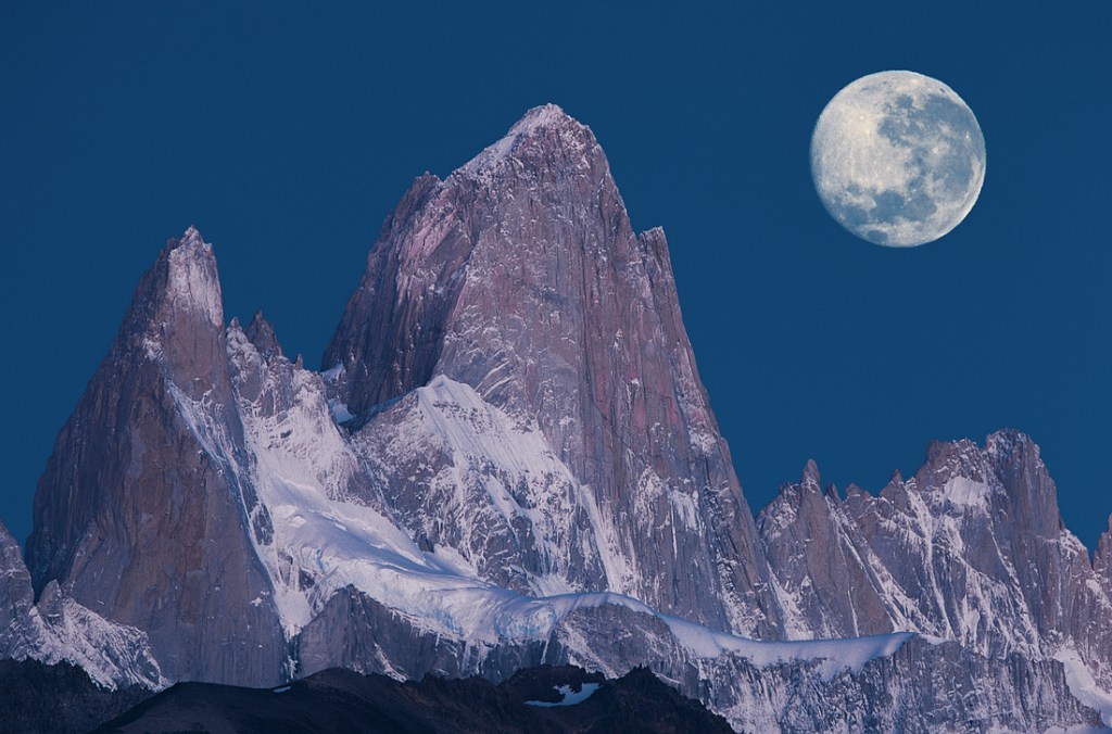 A full moon illuminates a granite spire. 