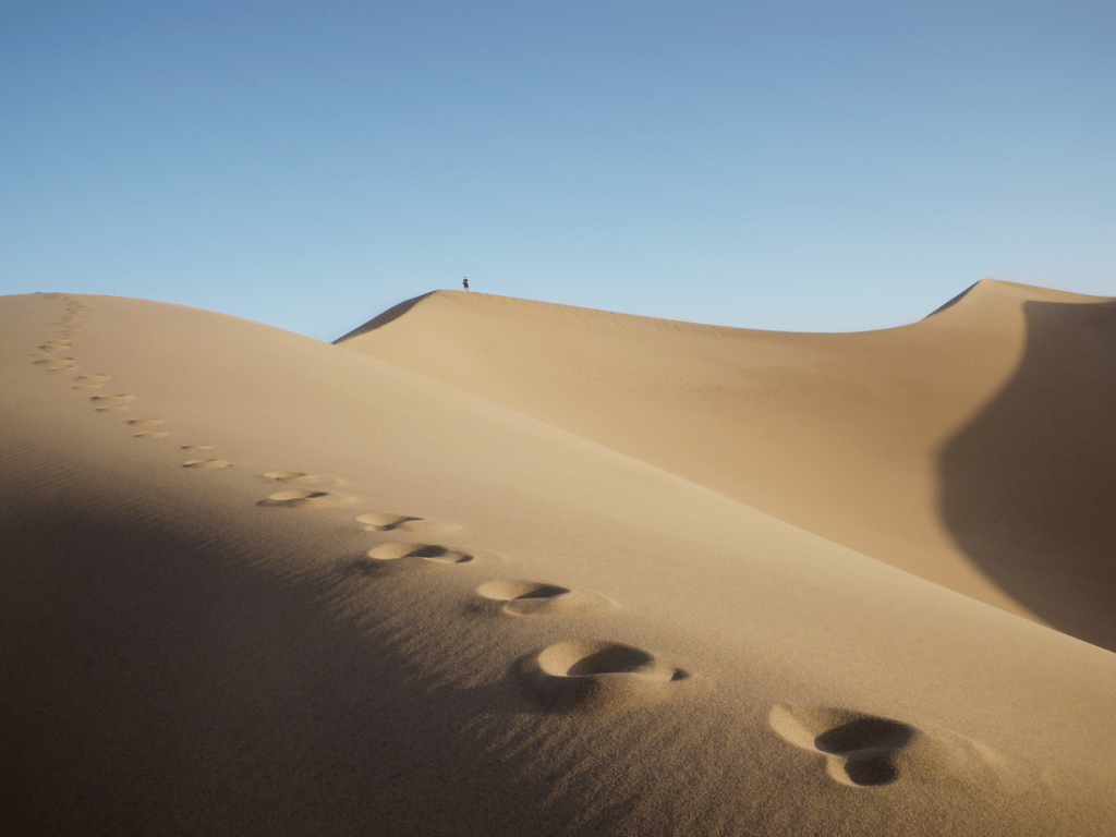 A hiker peaks a sand dune in Death Valley National Park.