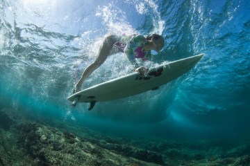 Shelby Stanger diving underwater on a surfboard.