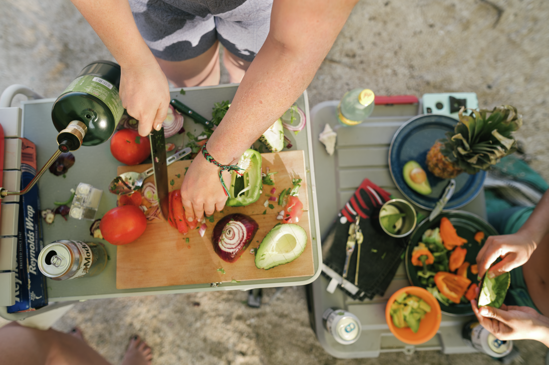 A person's hands are cutting vegetables outdoors.
