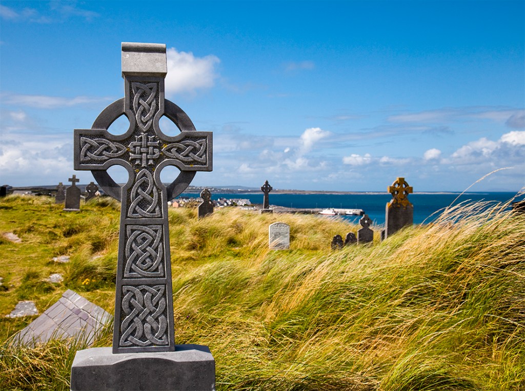 A grave sits in front of the Irish coastline. 