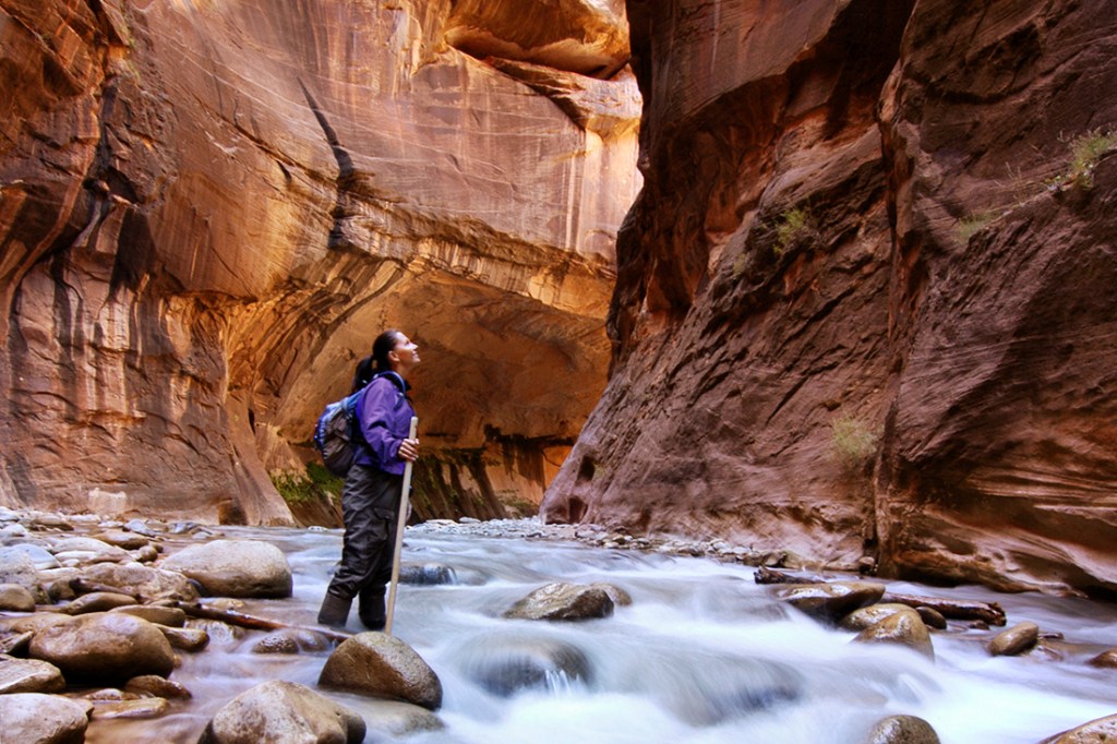 A hiker plods through The Narrows in Zion National Park.