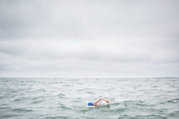 Kim Chambers swimming with a grey sky behind her.