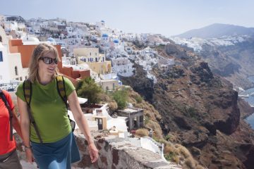 Travelers explore a white-washed urban landscape high above the Mediterranean.