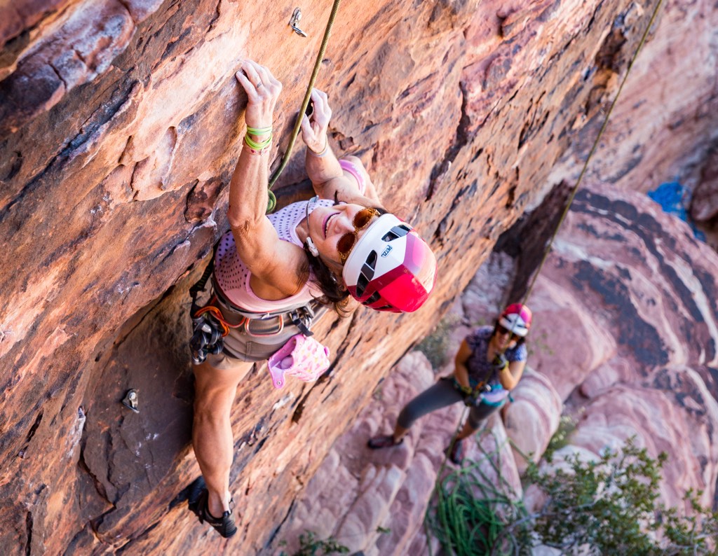 A climber smiles a big smile while reaching for the next hold while climbing on top rope.hing 