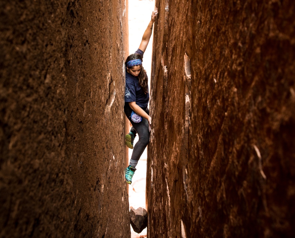 A climber wedges into a wide crack between two rock walls.