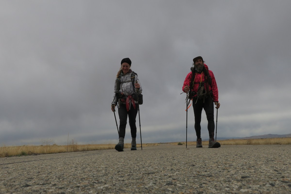 Two thru-hikers walk toward the camera on an abandoned road.