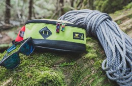 Sunglasses, waistpack and climbing rope lay on a mossy log.