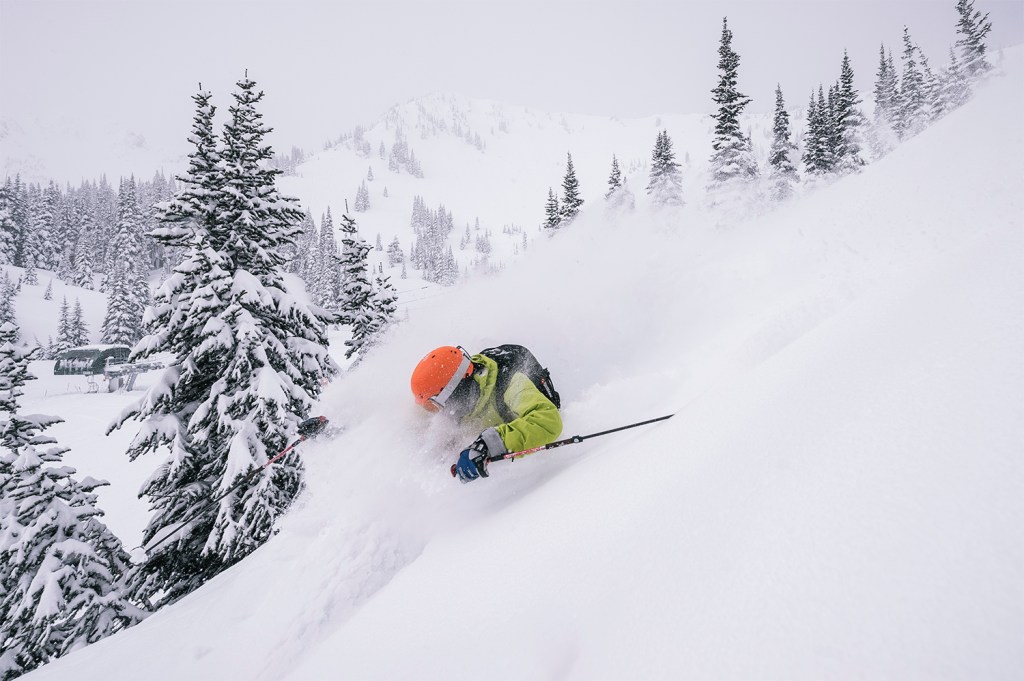 A skier slashed powder with a backpack on while riding inbounds terrain.