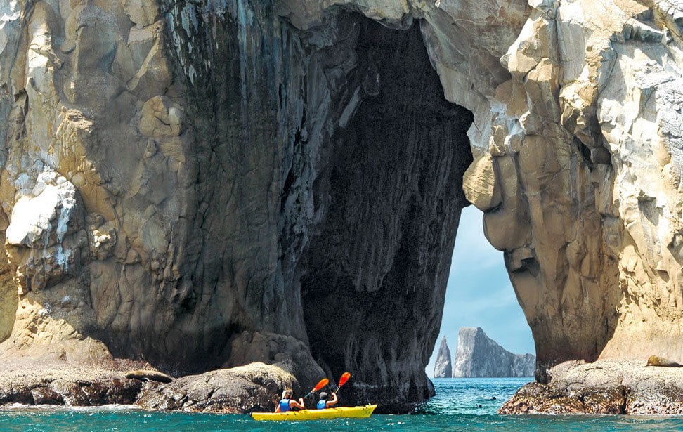 Kayakers on an REI Adventures trip paddle through sea cliffs. 