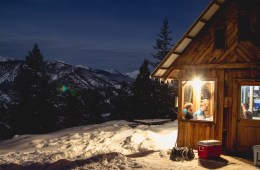 A hut is to the right side of the photo, lit up against the night sky.